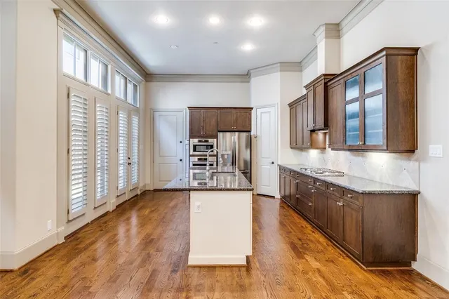 a large kitchen with stainless steel appliances granite countertop a large stove a sink dishwasher and a oven with wooden floor