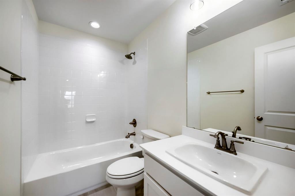 11548 Wulstone Road Haslet, TX 76052 - Photo 22 of 26 Bright bathroom featuring a white tub and shower combination with subway tile surround, single vanity with integrated sink, and bronze fixtures