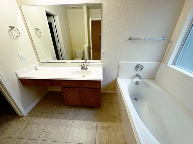 a bathroom with a tub sink and mirror