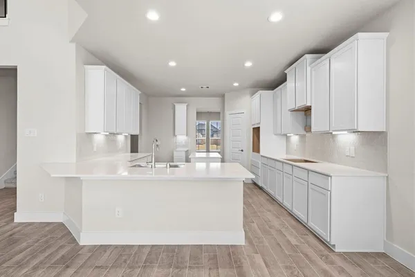 a large white kitchen with kitchen island a sink a center island stainless steel appliances and a cabinets