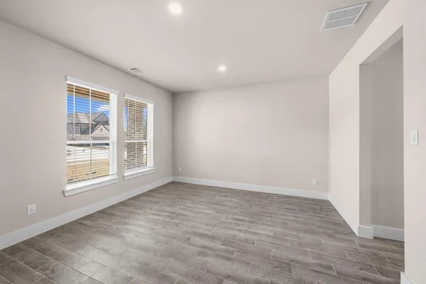 an empty room with wooden floor and windows