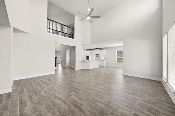 an empty room with wooden floor ceiling fan and windows