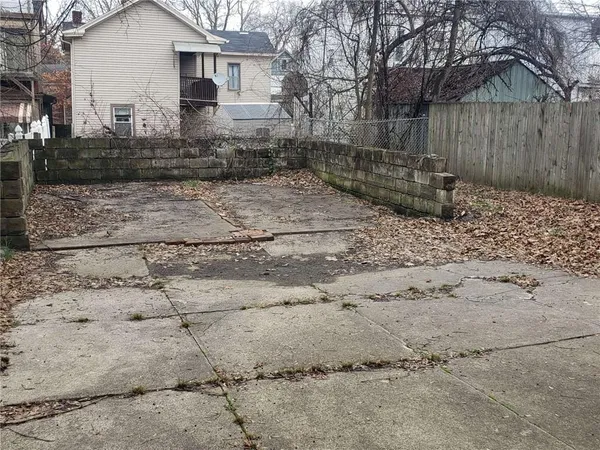 a view of a white house next to a yard with wooden fence