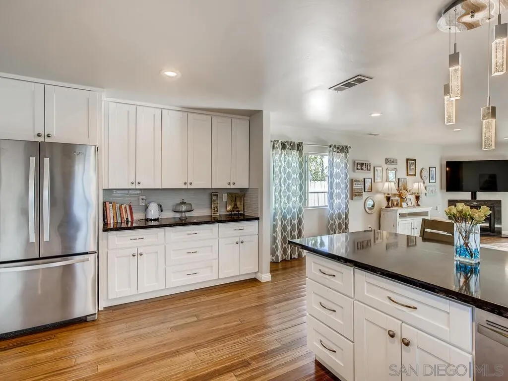 9559 Tuthill Way Santee, CA 92071 - Photo 20 of 27 a kitchen with stainless steel appliances granite countertop a refrigerator a sink dishwasher and white cabinets with wooden floor