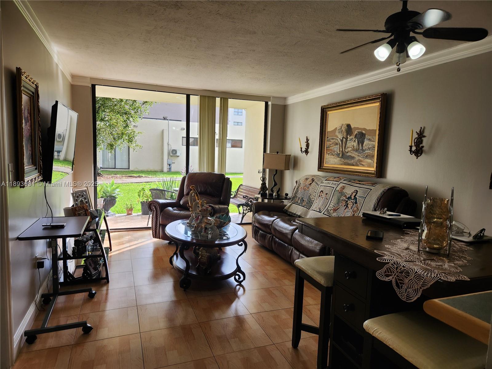 8000 Southwest 149th Avenue, Unit A107 Miami, FL 33193 - Photo 3 of 15 a living room with furniture floor to ceiling window and a flat screen tv