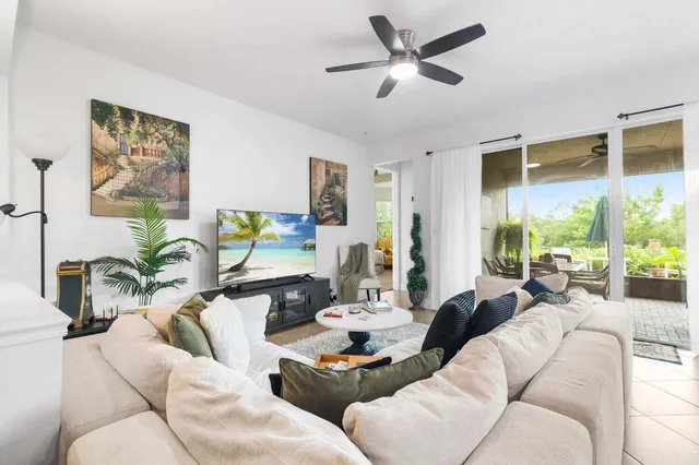 a living room with furniture ceiling fan and a large window