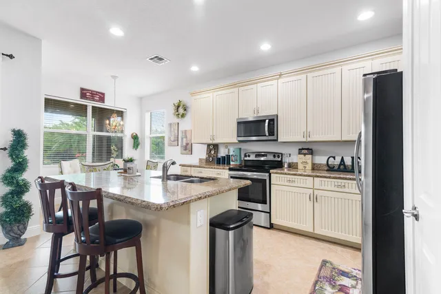 a kitchen with kitchen island granite countertop white cabinets and refrigerator