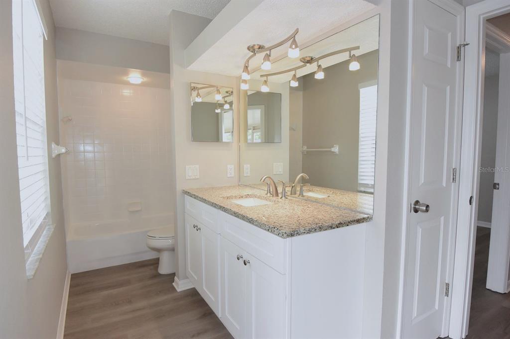 2339 Renton Lane Spring Hill, FL 34609 - Photo 24 of 35 a bathroom with a granite countertop sink a toilet and a mirror