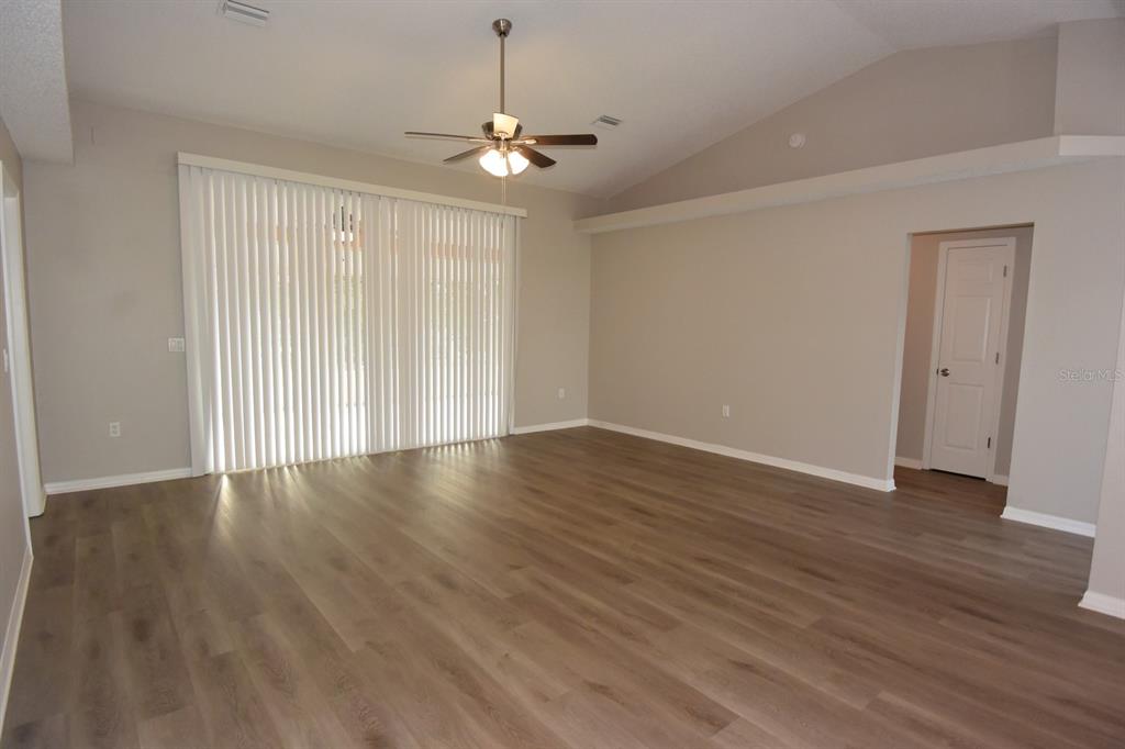 2339 Renton Lane Spring Hill, FL 34609 - Photo 4 of 35 a view of an empty room with wooden floor staircase and a kitchen