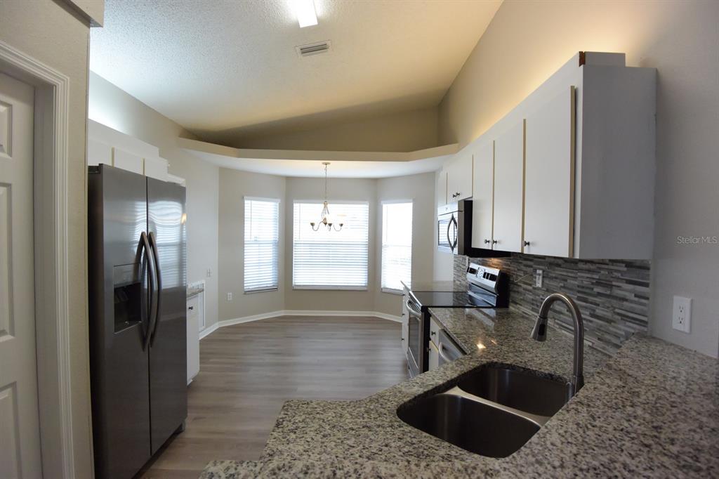 2339 Renton Lane Spring Hill, FL 34609 - Photo 9 of 35 a kitchen with stainless steel appliances granite countertop a sink a refrigerator and a granite counter tops