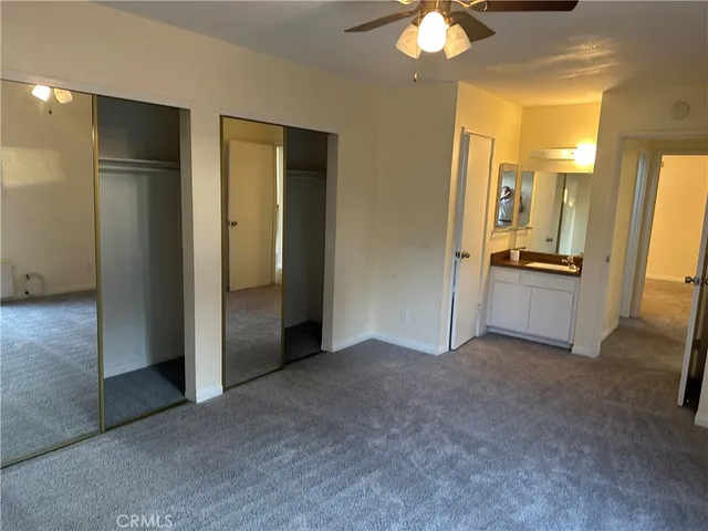 an empty room with closet and a chandelier fan