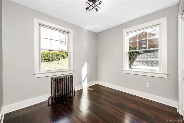 a view of an empty room with a window and wooden floor