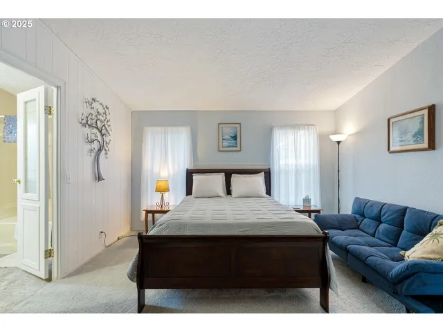 a bedroom with a bed window and a painting