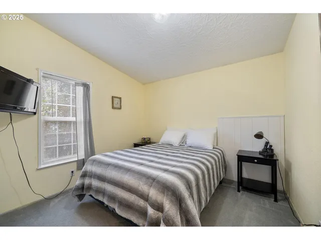 a bedroom with a bed and a flat tv screen on the dresser