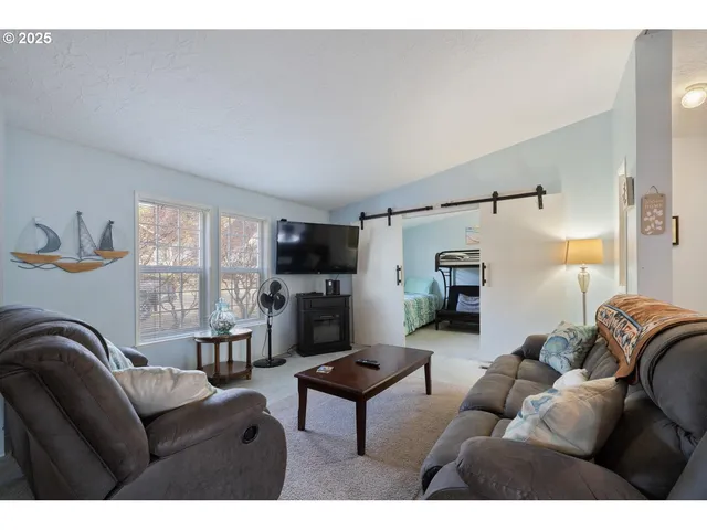a living room with furniture a flat screen tv and a window