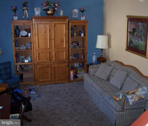 5986 Stephen Reid Road Huntingtown, MD 20639 - Photo 3 of 15 a living room with furniture a baby crib and a wooden chair