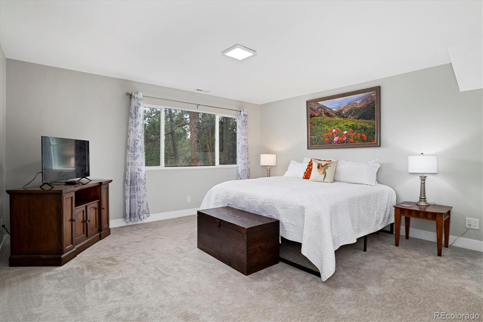 28867 Cedar Circle Evergreen, CO 80439 - Photo 10 of 35 a spacious bedroom with a bed and a flat screen television