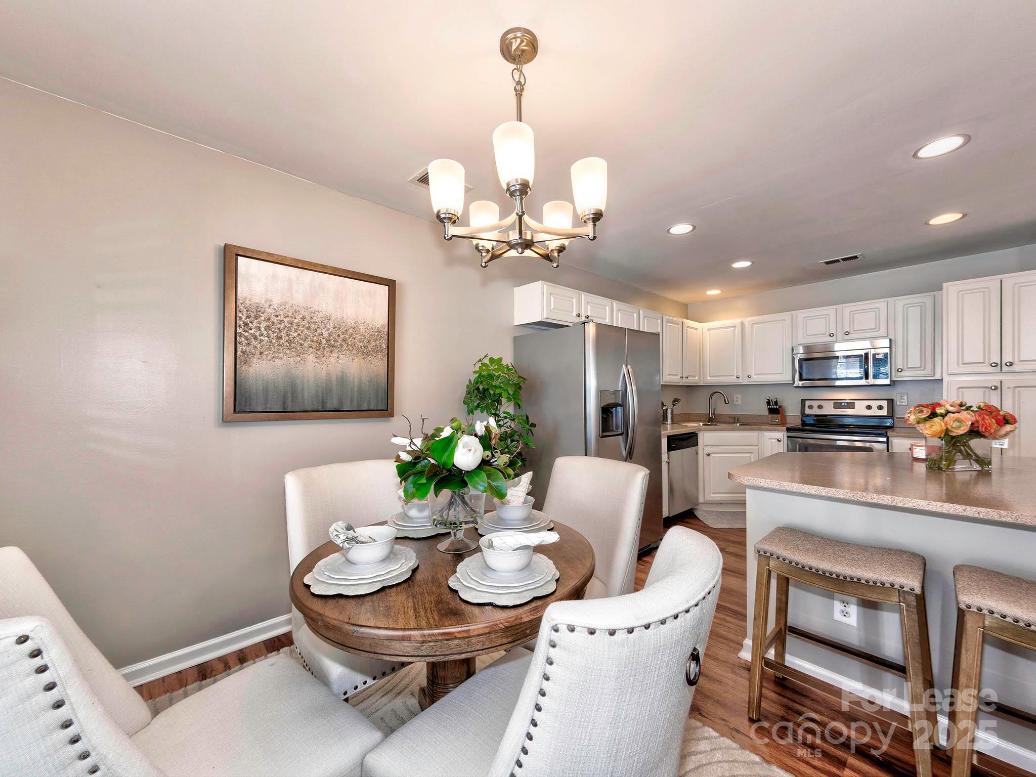 11316 Morgan Valley Lane Charlotte, NC 28270 - Photo 8 of 33 a kitchen with a dining table cabinets stainless steel appliances and a chandelier