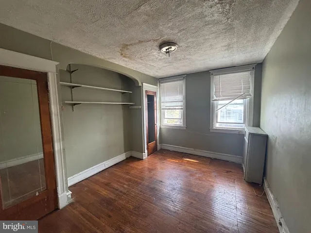 an empty room with wooden floor cabinet and windows