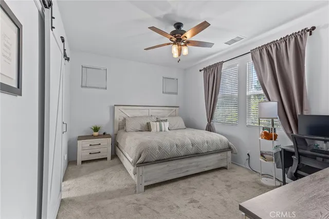 a bedroom with a bed a chandelier and a flat tv screen on dresser