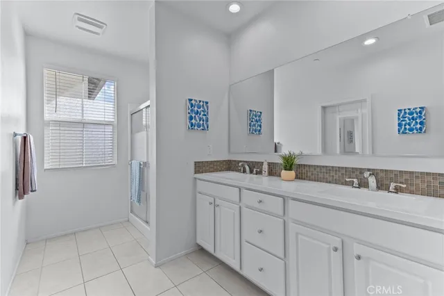 a spacious bathroom with a double vanity sink a mirror a shower and a bathtub