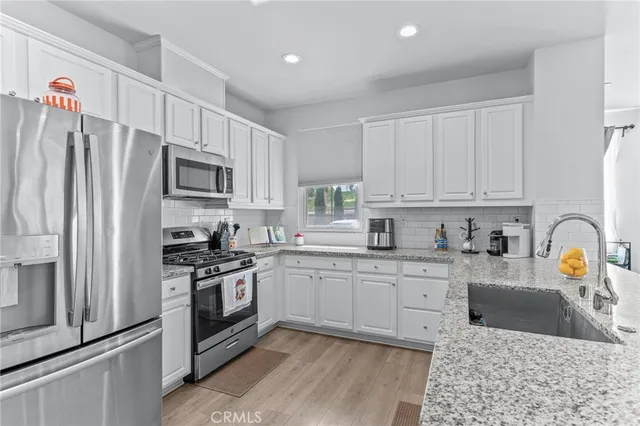 a kitchen with stainless steel appliances granite countertop a stove top oven a refrigerator a sink and dishwasher