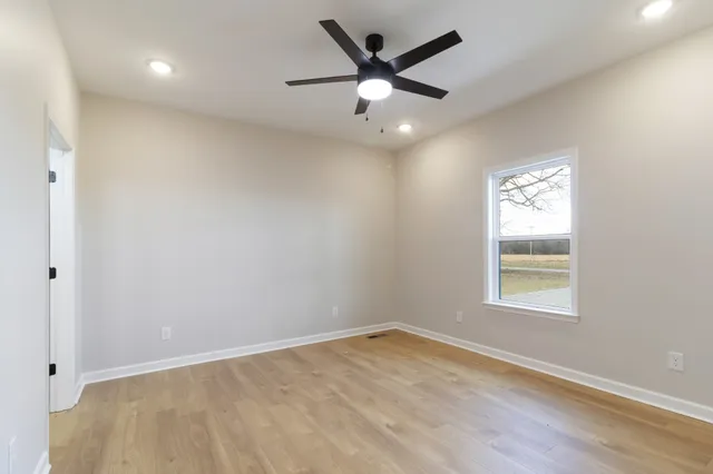 an empty room with a window and a fan