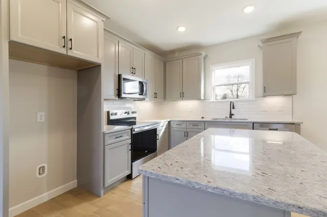 a kitchen with stainless steel appliances granite countertop a sink stove and refrigerator