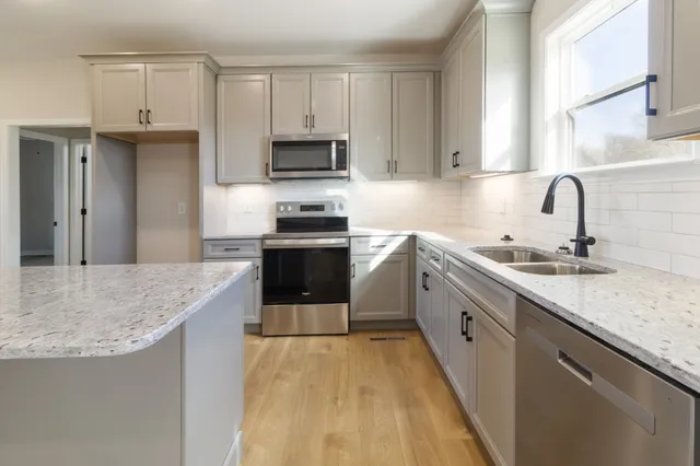 a kitchen with stainless steel appliances granite countertop a sink stove and refrigerator