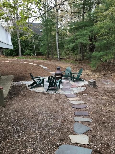 163 Greensward Road Mashpee, MA 02649 - Photo 27 of 37 a view of a patio with table and chairs under an umbrella with large trees