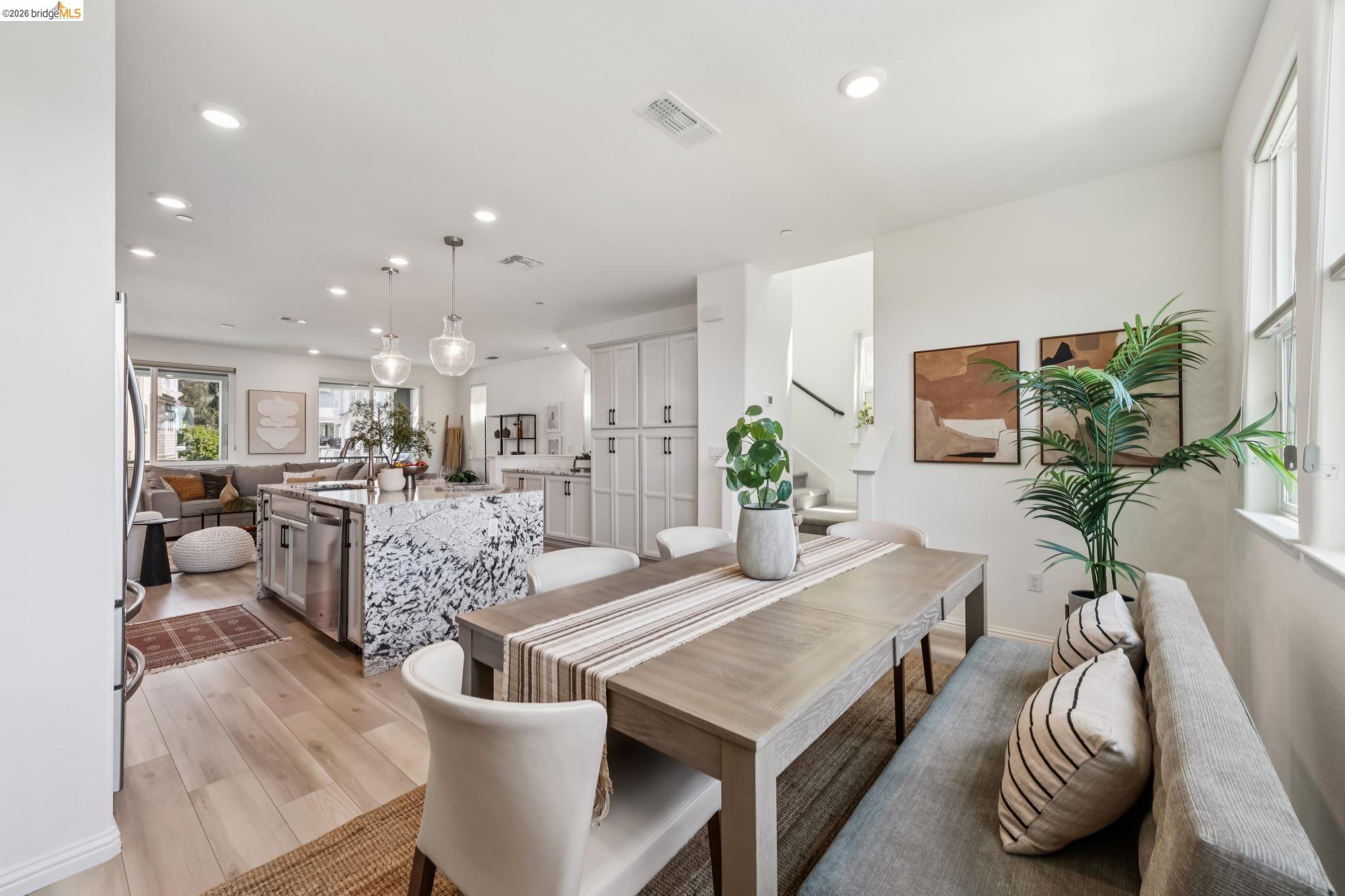 24157 Amaranth Loop Hayward, CA 94541 - Photo 29 of 63 Open-concept living space featuring wood-finish flooring, a kitchen island with a waterfall countertop, white cabinetry, recessed lighting, and a dining area with a built-in bench