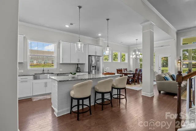 a kitchen with stainless steel appliances a refrigerator a sink a stove a dining table and chairs