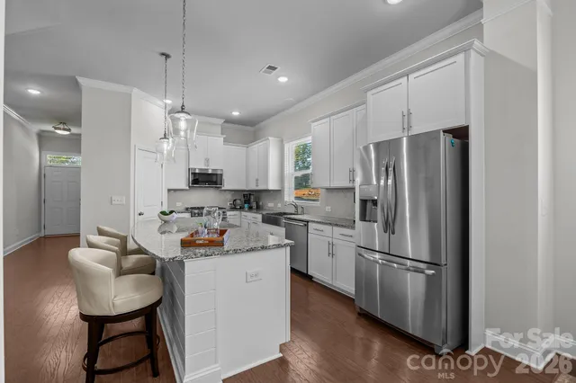 a large kitchen with granite countertop a large counter top a sink stainless steel appliances and cabinets