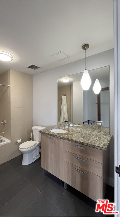 460 South Spring Street, Unit 1211 Los Angeles, CA 90013 - Photo 15 of 26 a bathroom with a granite countertop sink a toilet and a large mirror