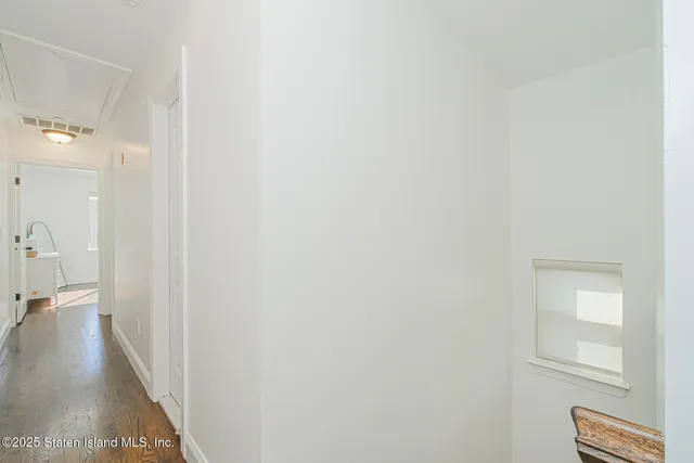a view of a hallway with wooden floor and a bathroom