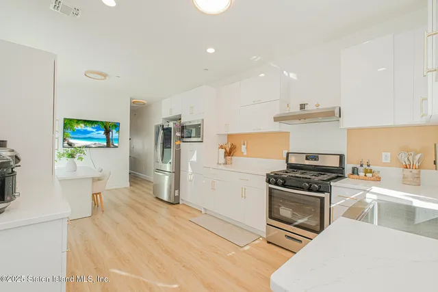 a kitchen with stainless steel appliances a stove a sink a refrigerator and a refrigerator