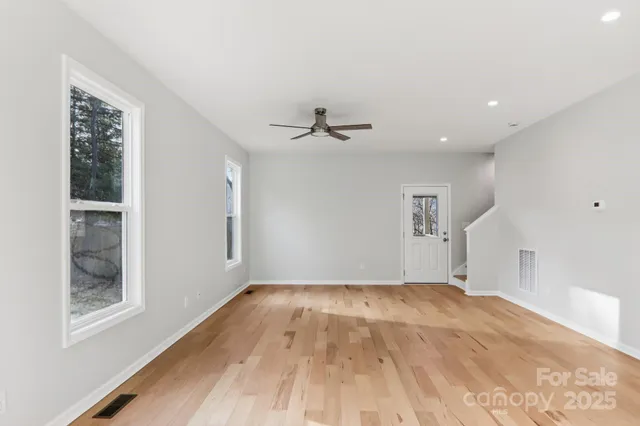 a view of a room with wooden floor and a ceiling fan