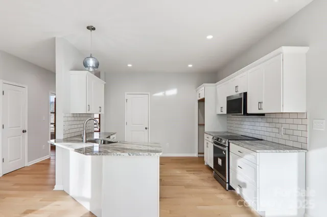 a large kitchen with stainless steel appliances kitchen island granite countertop a lot of counter space and wooden floor