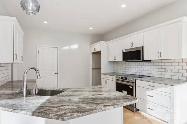 a kitchen with stainless steel appliances granite countertop a stove top oven a sink and dishwasher