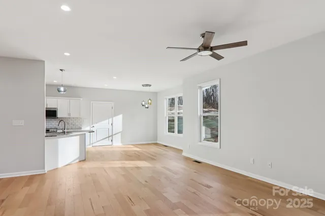 a view of empty room with wooden floor and kitchen