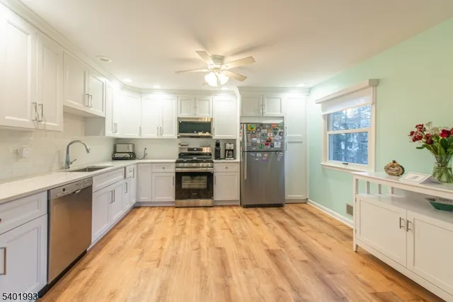 a white kitchen with wooden floor and stainless steel appliances