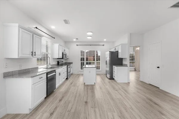 a large kitchen with stainless steel appliances refrigerator a stove top oven and wooden floors