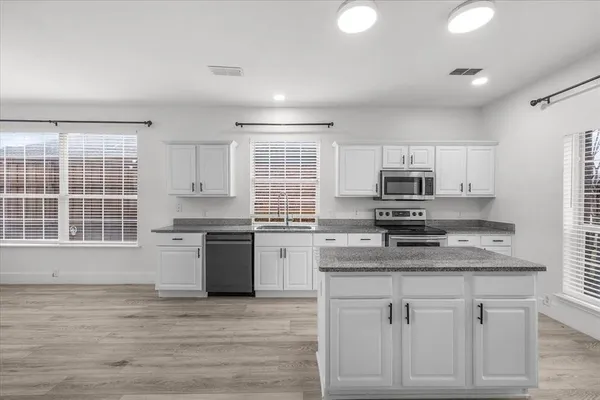 a kitchen with stainless steel appliances granite countertop a kitchen island hardwood floor sink stove and granite counter top