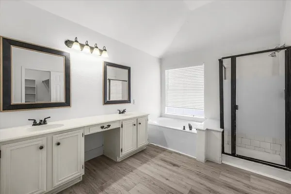 a spacious bathroom with a double vanity sink a mirror and a bathtub