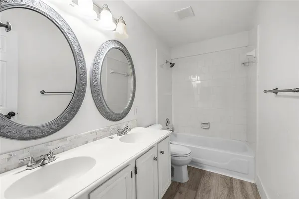 a bathroom with a granite countertop toilet a sink and a mirror