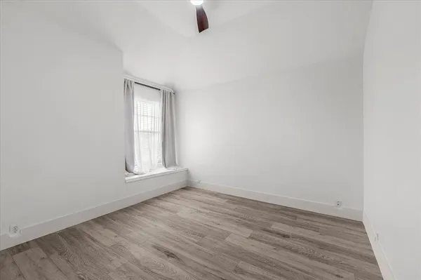 an empty room with wooden floor cabinet and windows
