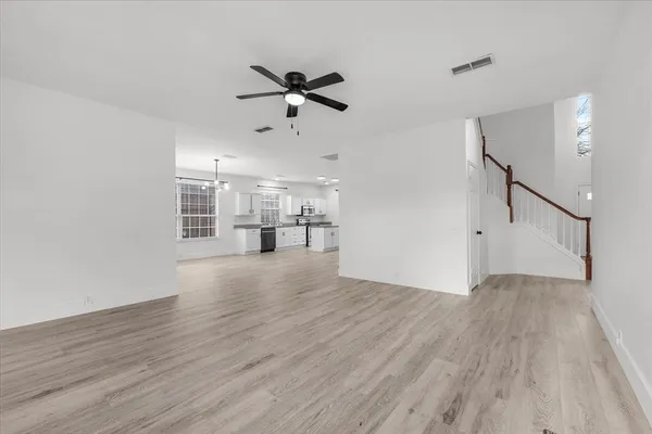 a view of a room with wooden floor staircase and a kitchen