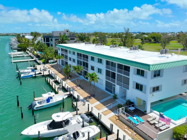 a kitchen with stainless steel appliances granite countertop a refrigerator a sink dishwasher a stove and a dining table with wooden floor