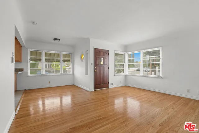 a view of an empty room with a window and wooden floor