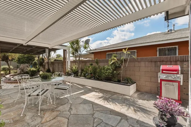 a patio with table and chairs and potted plants